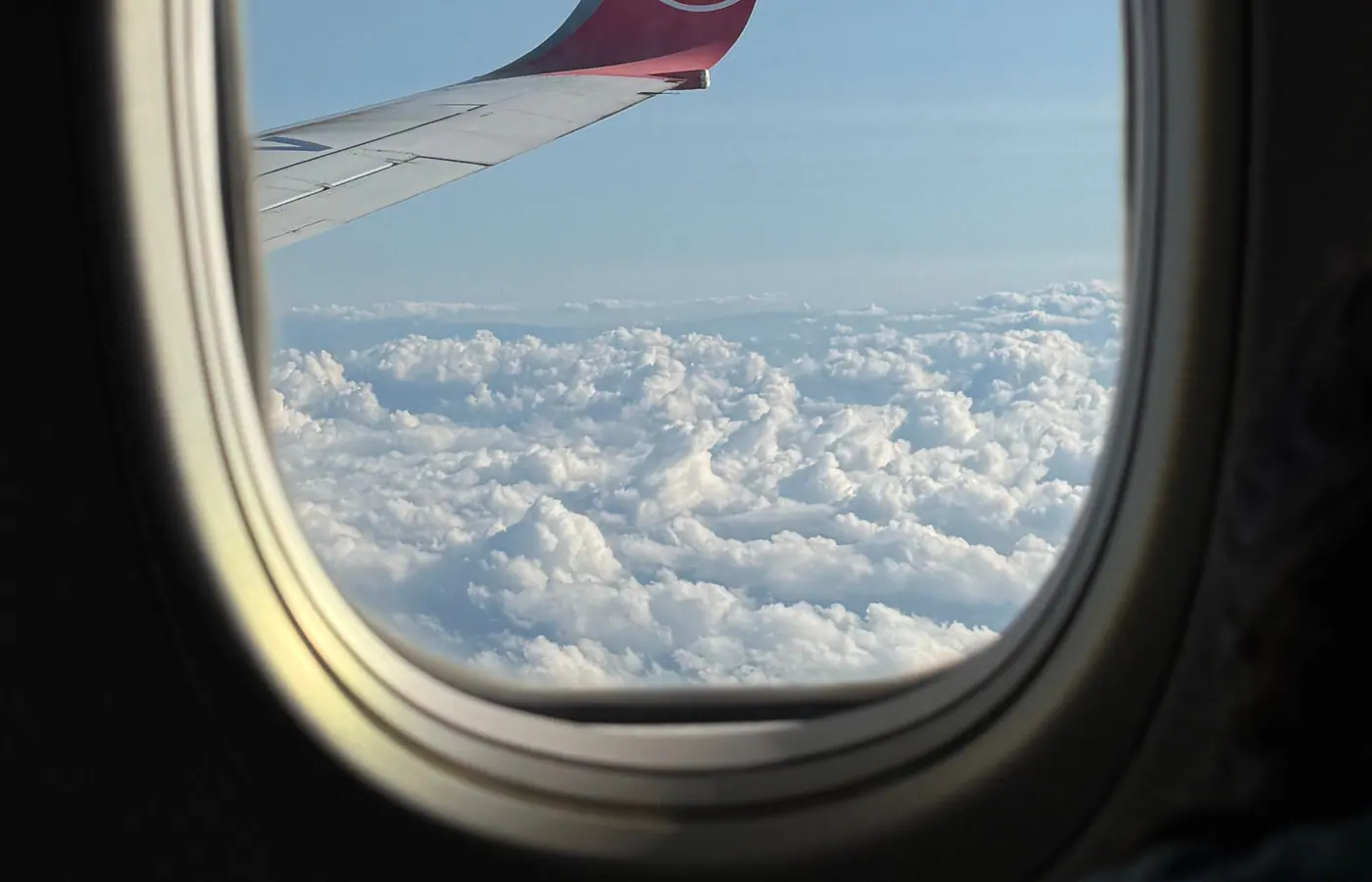 Blick aus dem Flugzeug auf Tragfläche und Wolken während eines Fluges